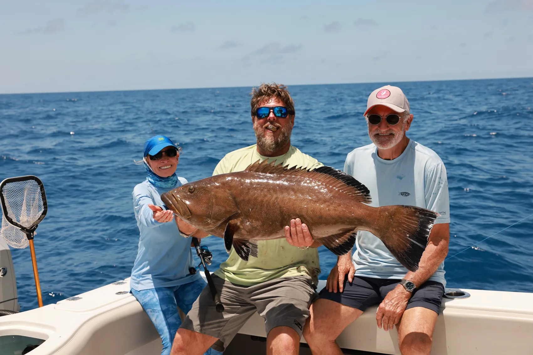 Three anglers holding up a big catch aboard a Deep End Charters boat